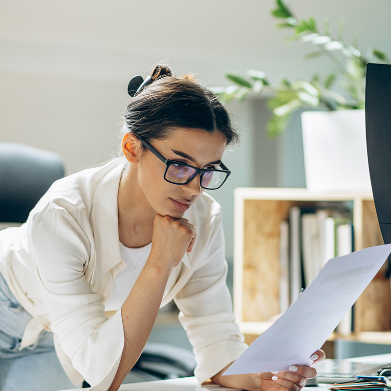 Chica observando una hoja de papel en una oficina